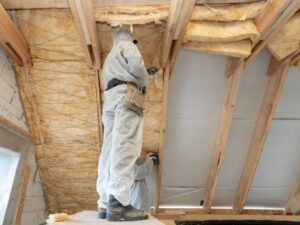Workers installing fiberglass insulation in a vaulted ceiling.