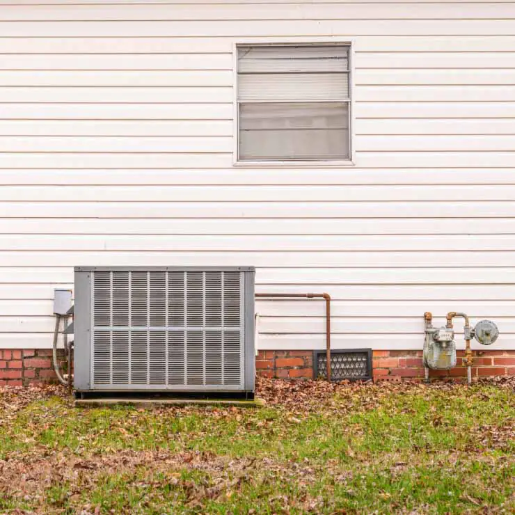 Residential air conditioning unit, pictured outside home's wall.